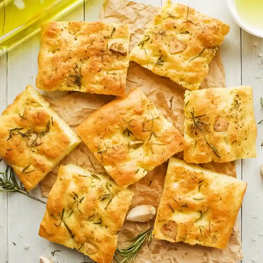 A golden-brown focaccia bread topped with fresh rosemary, olive oil, and flaky sea salt, perfect as a side or snack.
