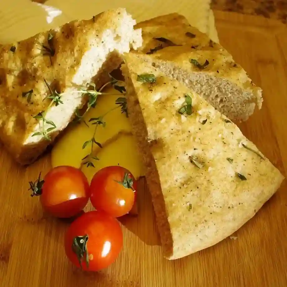 A golden-brown focaccia bread topped with fresh rosemary, olive oil, and flaky sea salt, perfect as a side or snack.