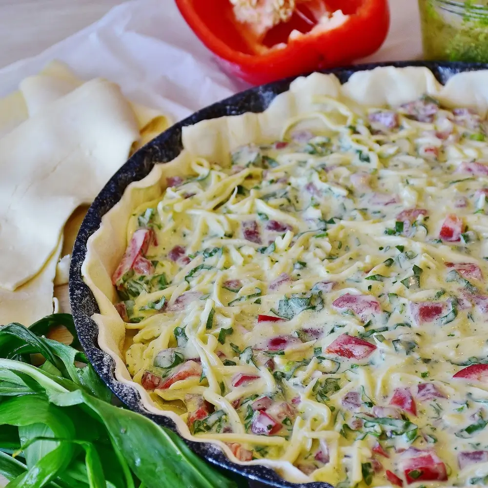 A slice of tortilla quiche bake with layers of eggs, cheese, and vegetables, served on a plate.