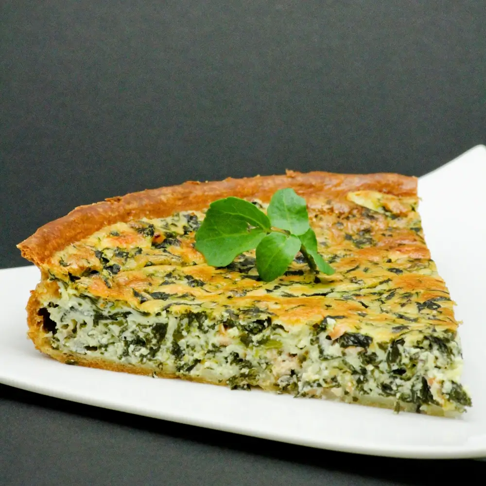A slice of tortilla quiche bake with layers of eggs, cheese, and vegetables, served on a plate.