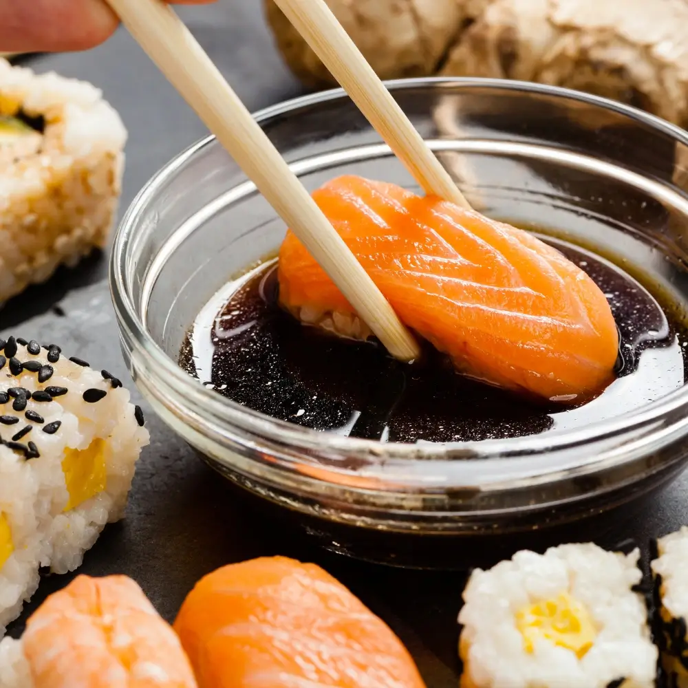 A bottle of homemade soy sauce, rich in color and texture, next to a small dish for serving.