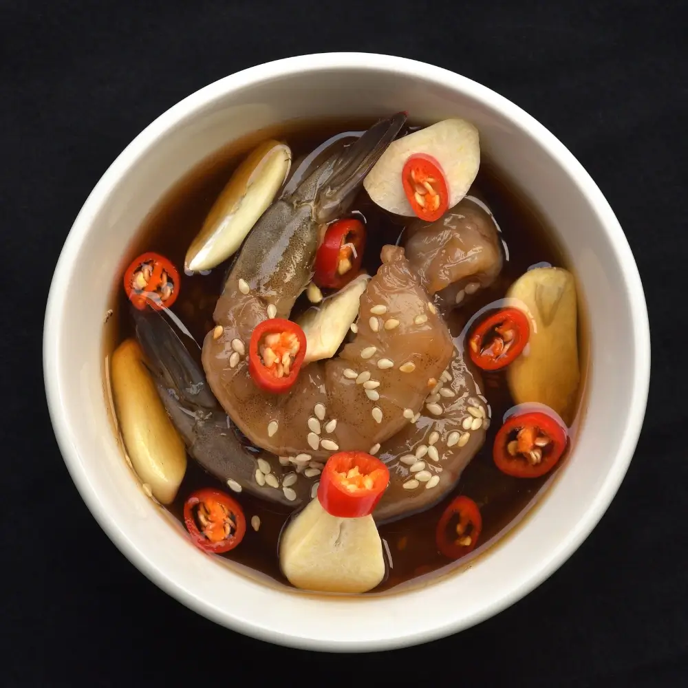 A bottle of homemade soy sauce, rich in color and texture, next to a small dish for serving.